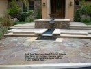 Light Sand Wash Concrete with Pre-Cast Concrete  Step Treads and Wall Caps. Flagstone Field in  Foreground with Ledgestone Veneer on Water  Feature to Match House